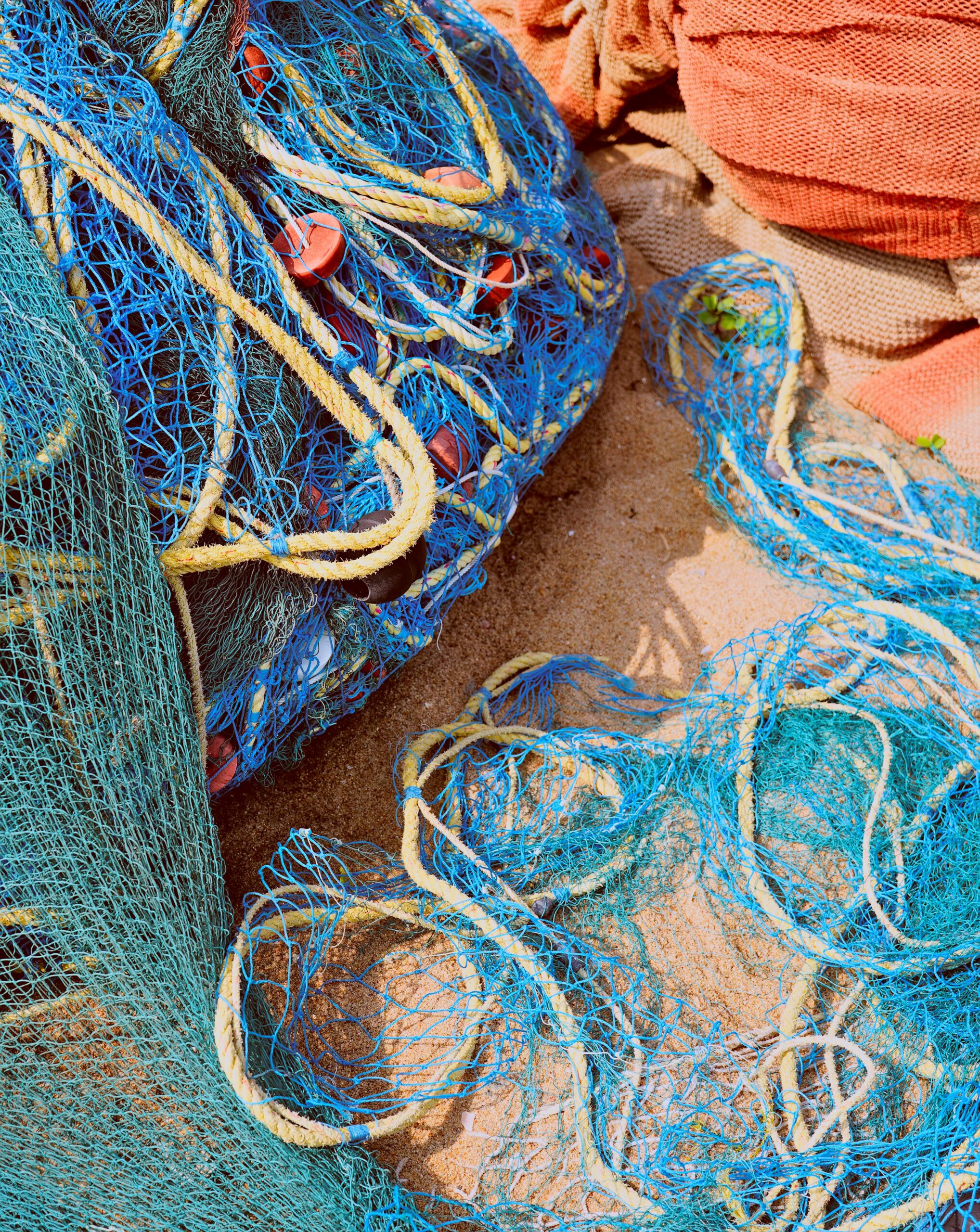 a pile of blue fishing nets sitting on top of a sandy beach